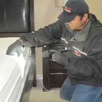 Bed bug inspection technician checking a mattress and bed frame for signs of infestation in Memphis, TN