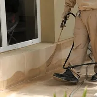 General pest control technician spraying exterior perimeter around a home in Memphis, TN