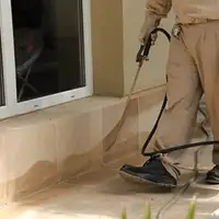 General pest control technician spraying exterior perimeter around a home in Memphis, TN
