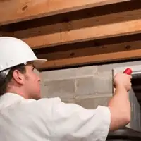 Termite inspection technician checking a basement wall and framing for termite activity in Memphis, TN